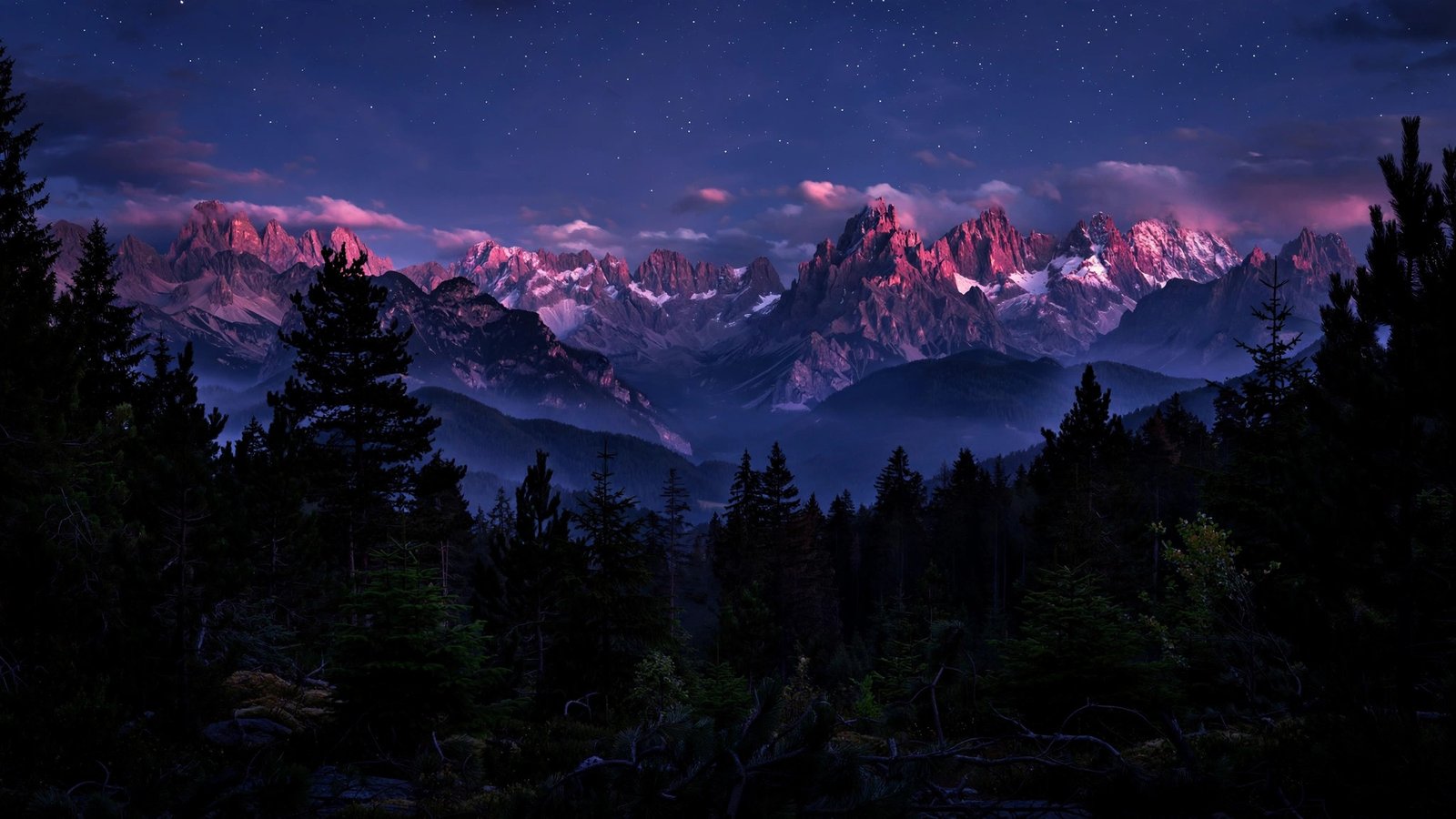 Rugged peaks glowing pink and violet in dusk alpenglow under stars