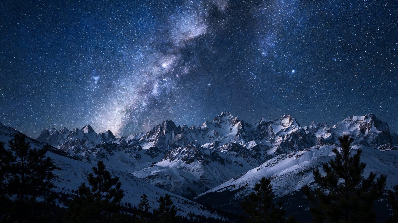 Snow-covered summits under the Milky Way in a starry night sky